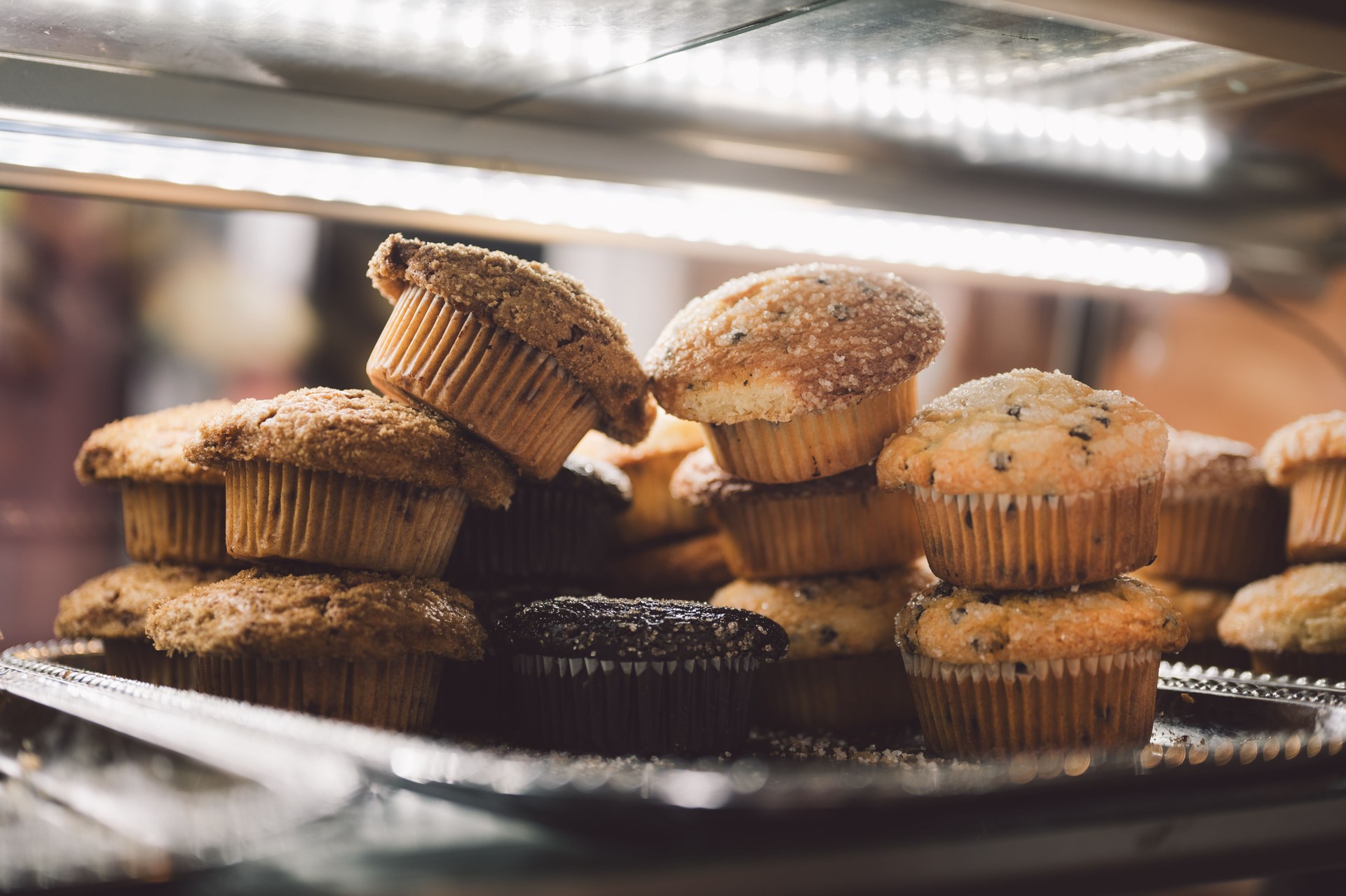 "Assorted Muffins in a Bakery Display Case with Warm Lighting